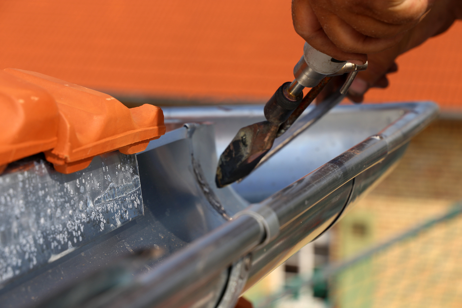 Roofer doing plumbing work on a gutter